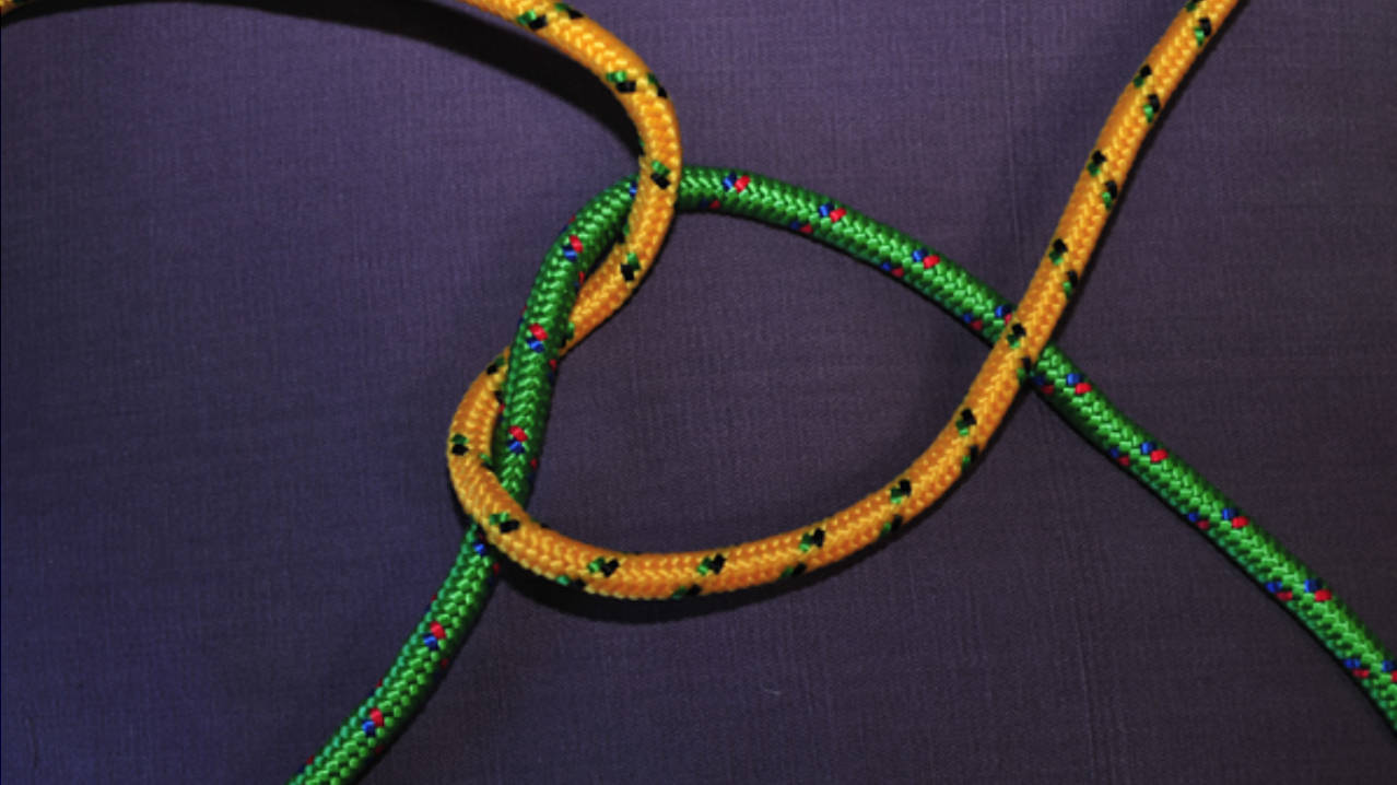 Photograph of some green and yellow rope on a table, arranged in a tangle